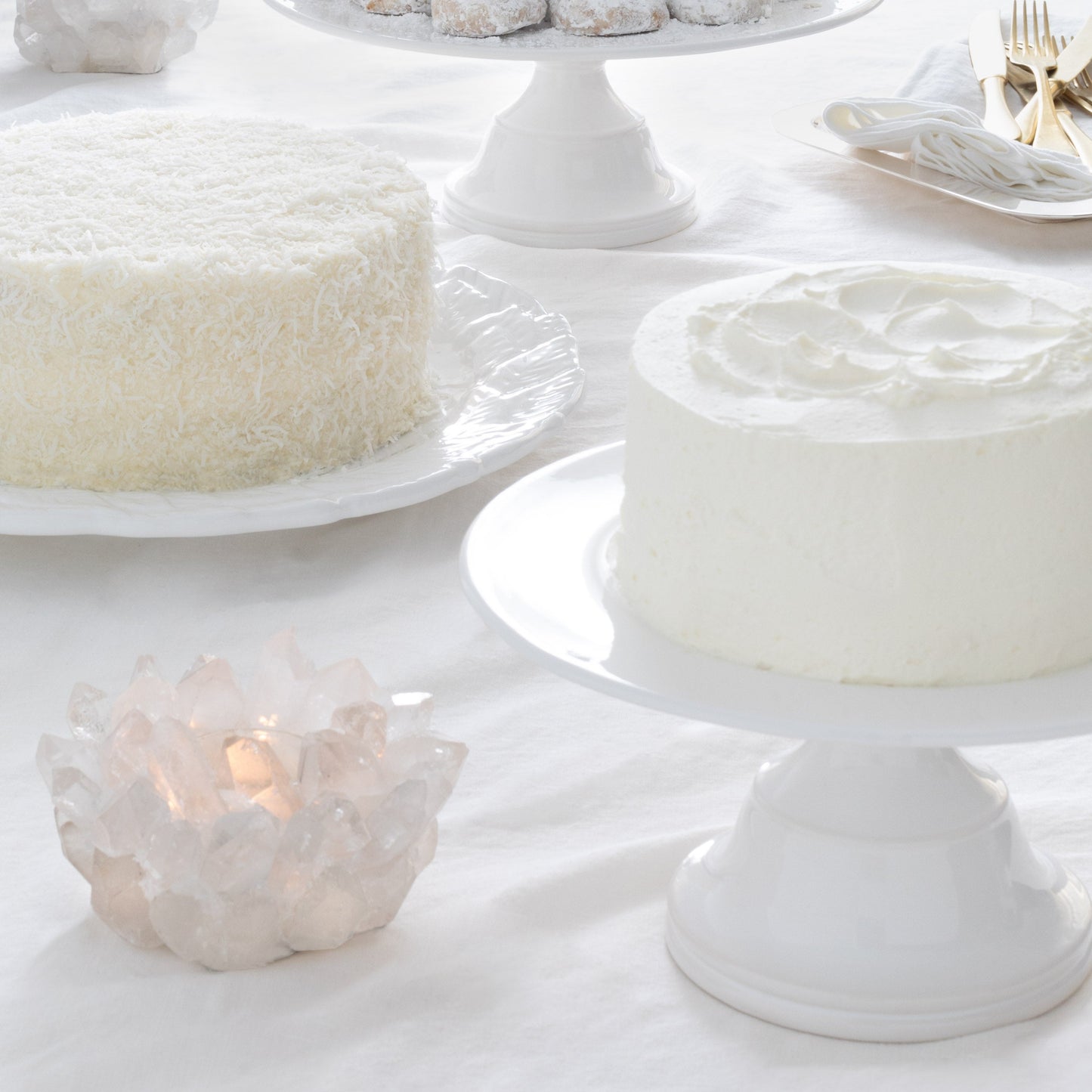 Small white ceramic pedestal cake stand with a frosted cake.