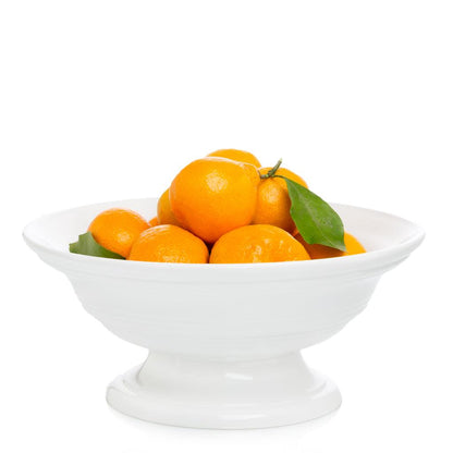 White ceramic footed bowl, 11.5"Dia. x 6"H, filled with oranges and green leaves.