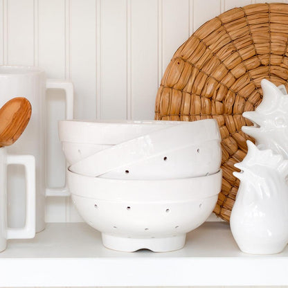 Hudson Grace white ceramic colander, vintage-inspired, with drainage holes, stacked on a white shelf.
