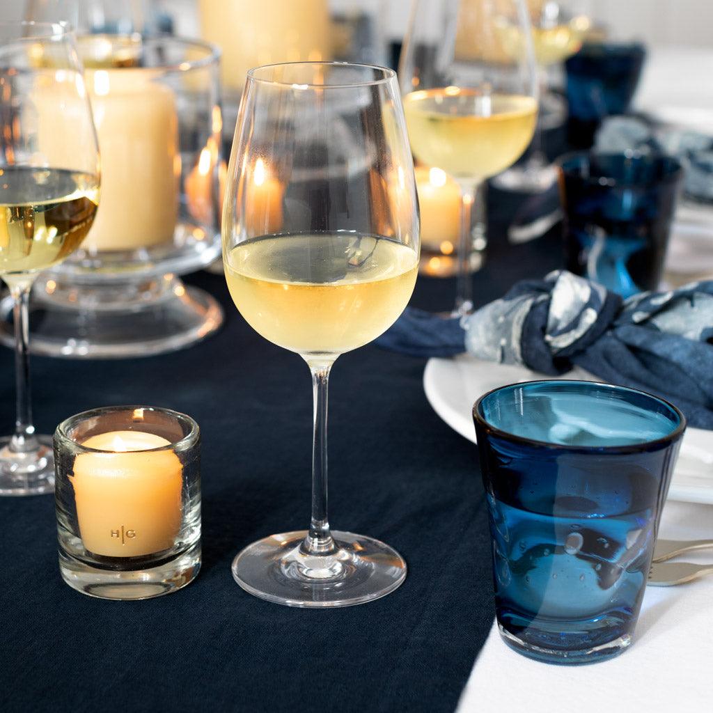 Indigo Henri mouth-blown glass, 8 oz, on a table with wine glasses and candles.