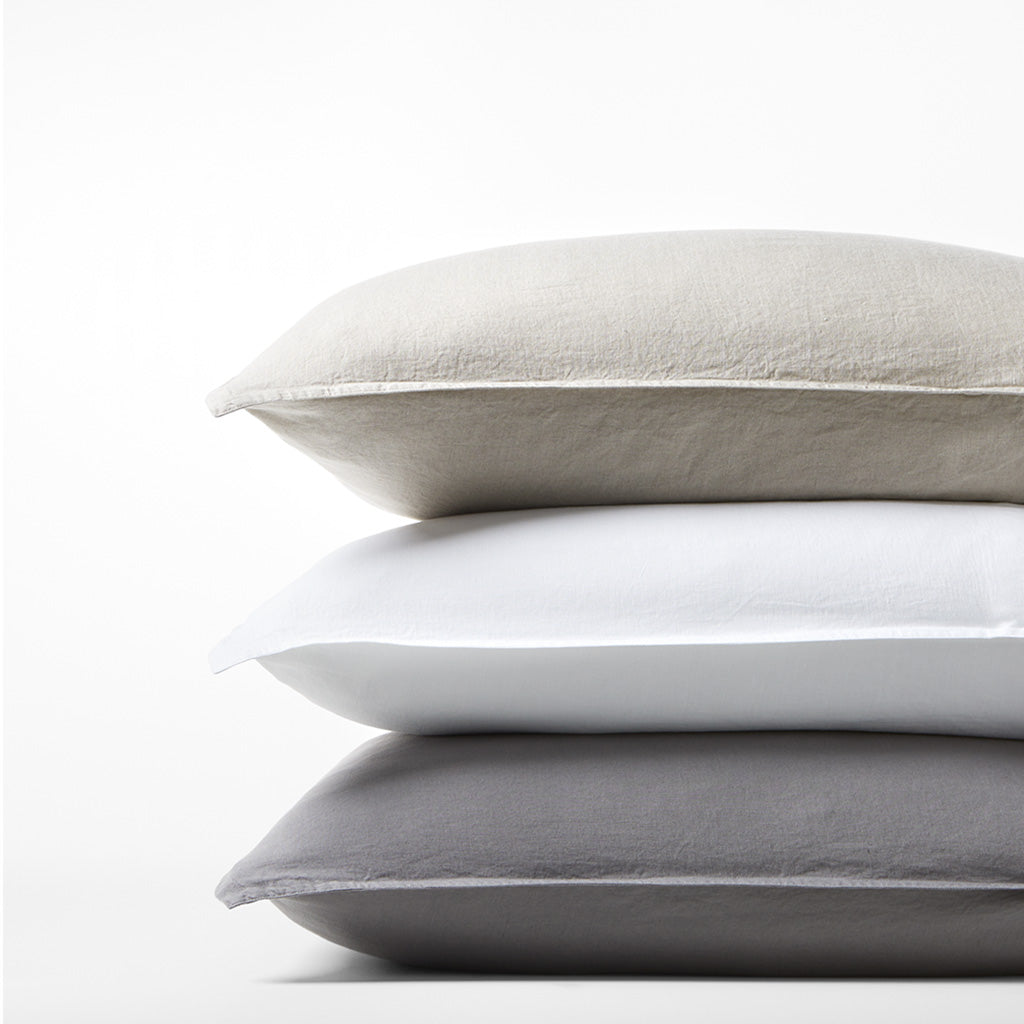 Stack of three Washed-Linen Pillow Shams: khaki, white, and dark gray, with a relaxed texture.