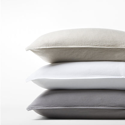 Stack of three Washed-Linen Pillow Shams: khaki, white, and dark gray, with a relaxed texture.