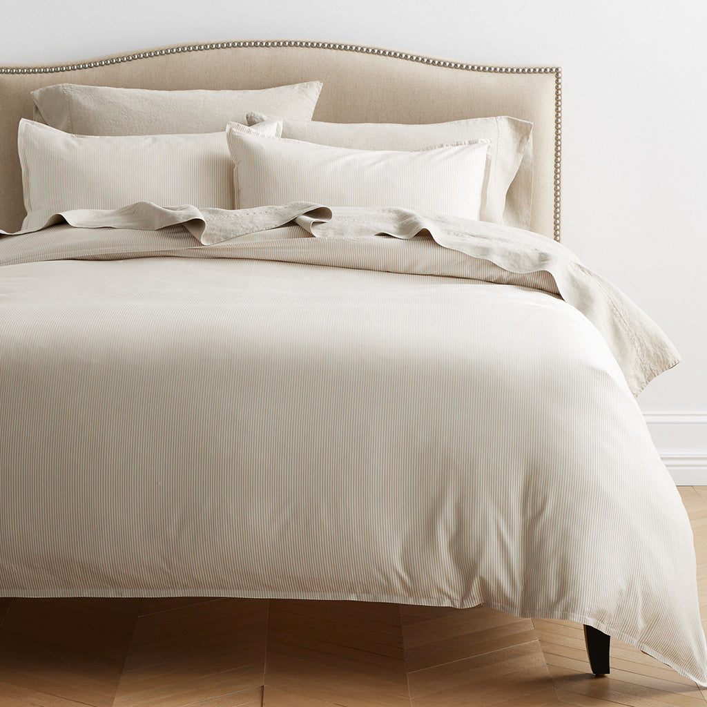 Khaki Stripe Cotton-Chambray Pillow Shams, set of 2, on a bed with matching striped duvet.