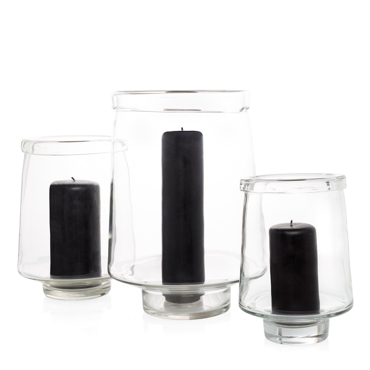 Three clear glass Antwerp hurricane candle holders, varying sizes, each with a black pillar candle.