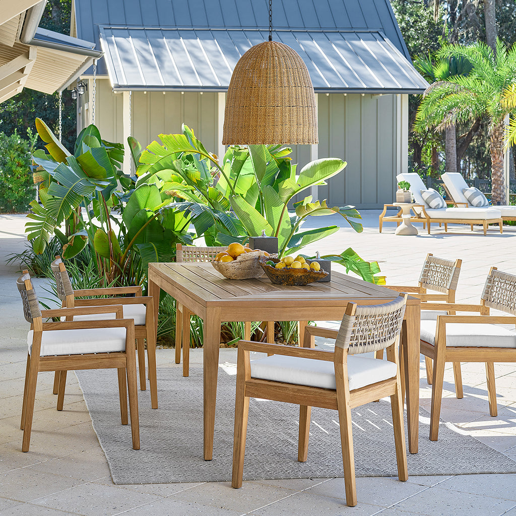 Large outdoor beehive pendant light made of rattan-like material, hanging over a wooden dining set.