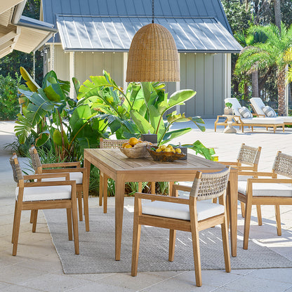 Large outdoor beehive pendant light made of rattan-like material, hanging over a wooden dining set.
