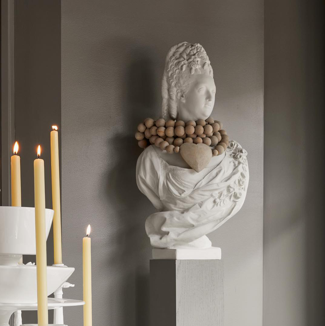 White resin Marie Antoinette bust with period clothing, high wig, and wooden beaded necklace.