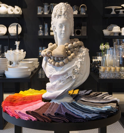White resin bust of Marie Antoinette with a beaded necklace, surrounded by colorful linen napkins.