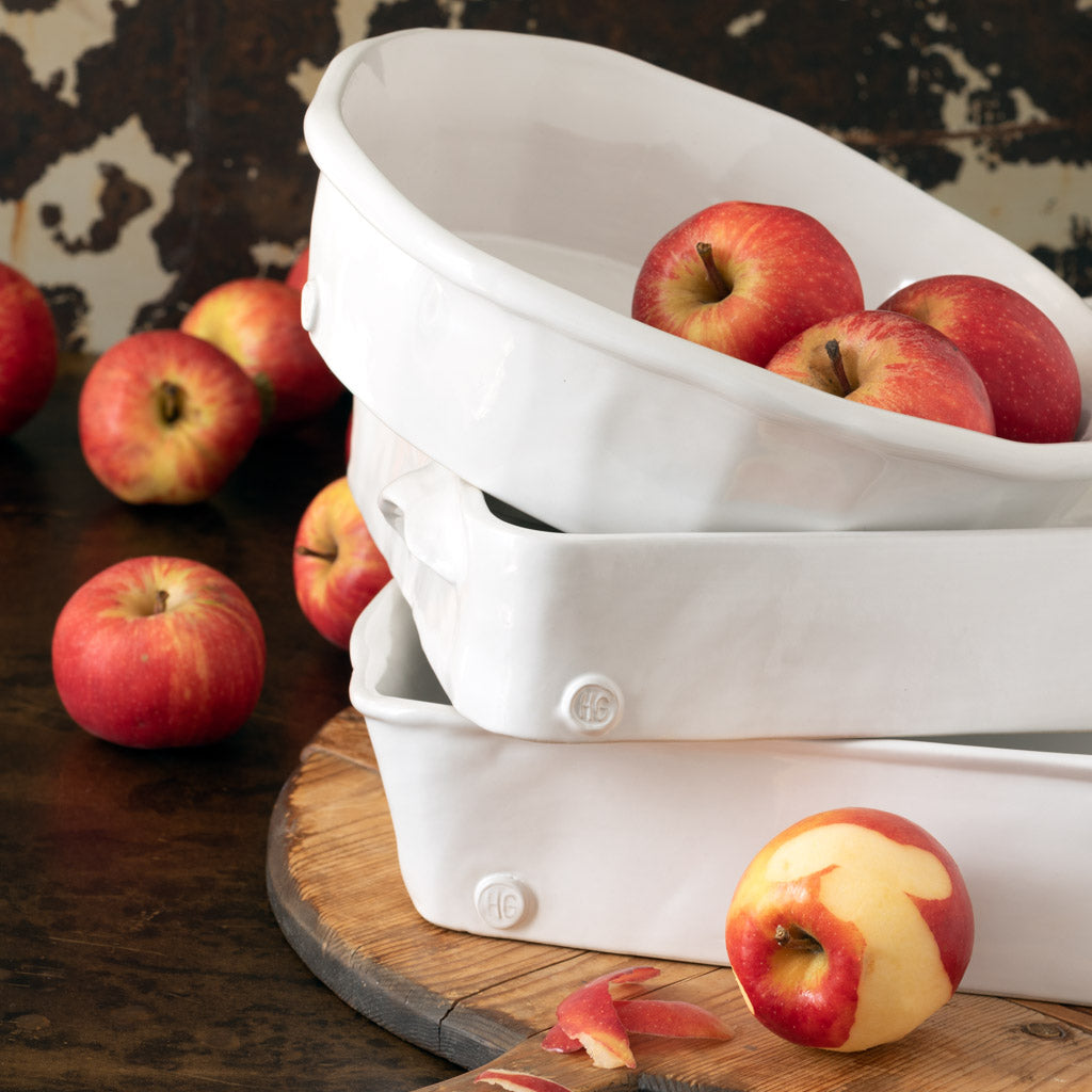 Stack of three creamy white Montes Doggett handmade ceramic rectangular baking dishes with apples.