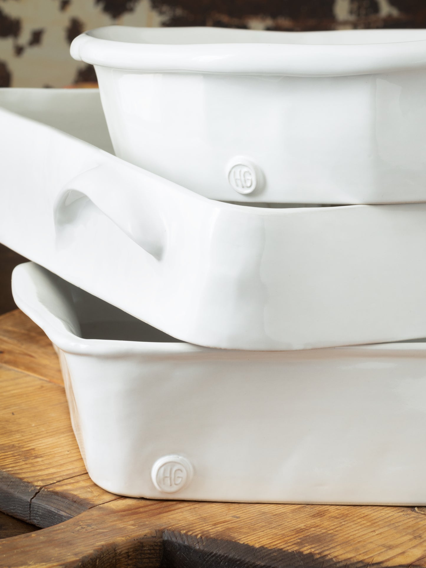 Stack of three creamy white HG Montes Doggett handmade ceramic baking dishes with handles.
