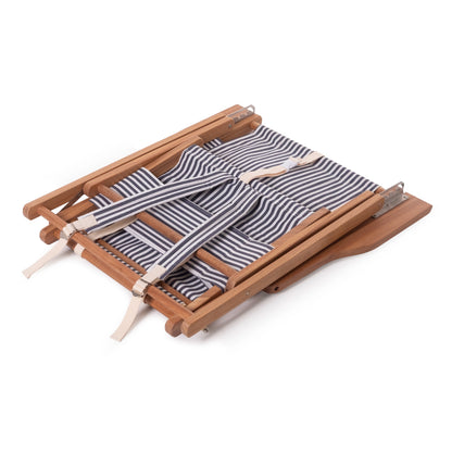 Folded Navy and White Stripe Canvas Reclining Outdoor Beach Chair with teak frame and backpack straps.