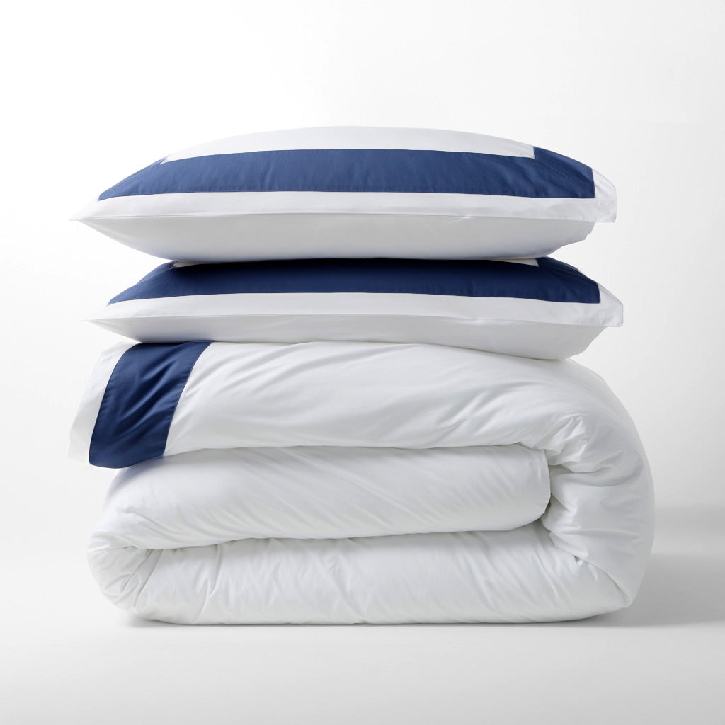 Navy blue wide-band percale duvet cover and two shams, stacked.