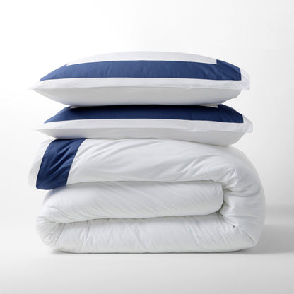 Navy blue wide-band percale duvet cover and two shams, stacked.