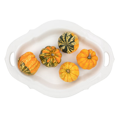White ceramic Nonna serving platter with decorative handles, holding five small colorful gourds.