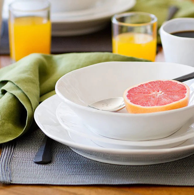 White ceramic Organic Low Bowl with grapefruit, on a plate, with green napkin and drinks.