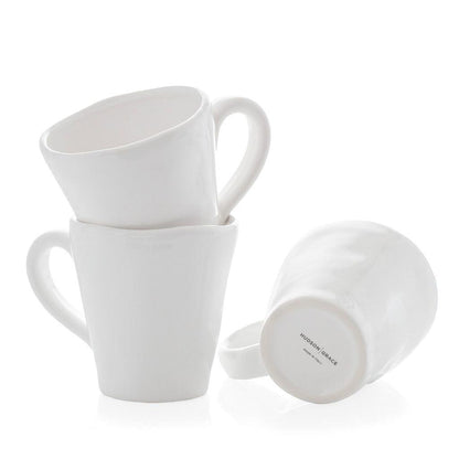Stacked white ceramic mugs with organic edges, one showing "Hudson Grace Made in Italy" on the base.
