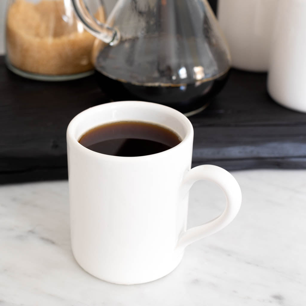 HG Original creamy white ceramic mug with coffee, 4" Diameter x 5"H, on a marble surface.