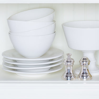 Stacked HG Original creamy white ceramic salad plates, bowls, and a footed bowl with two silver shakers.