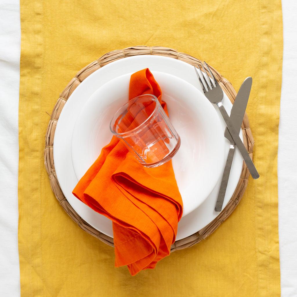 HG Original 10" creamy white ceramic bowl on a woven placemat, with an orange napkin, glass, and silverware.