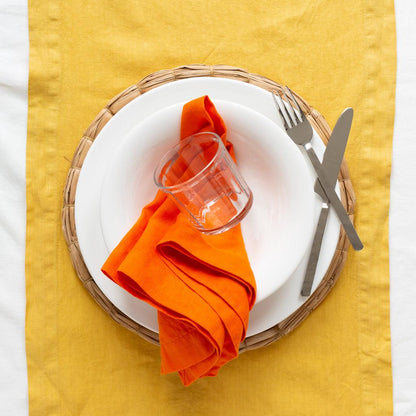 HG Original 10" creamy white ceramic bowl on a woven placemat, with an orange napkin, glass, and silverware.