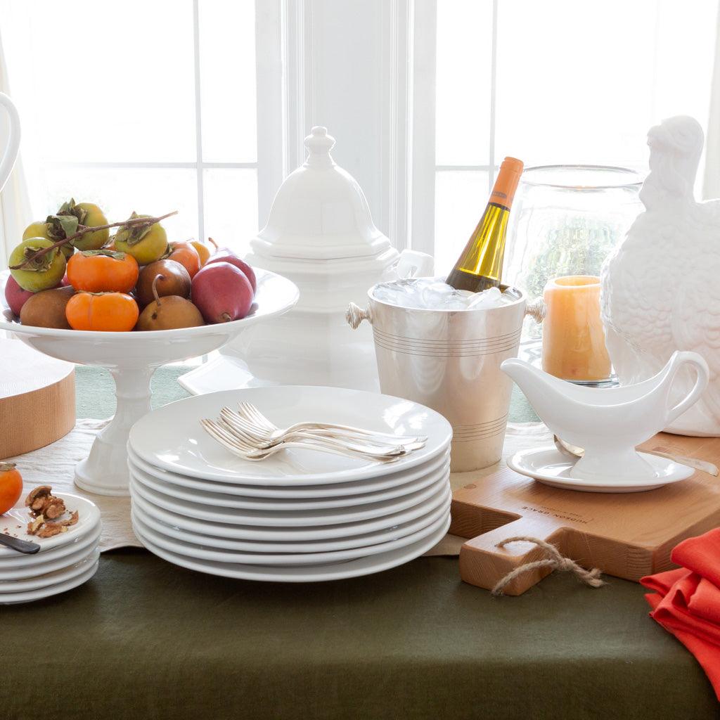 HG Original Pedestal Serve Bowl, creamy white ceramic, 15" Dia x 9" H, filled with fruit on a table setting.