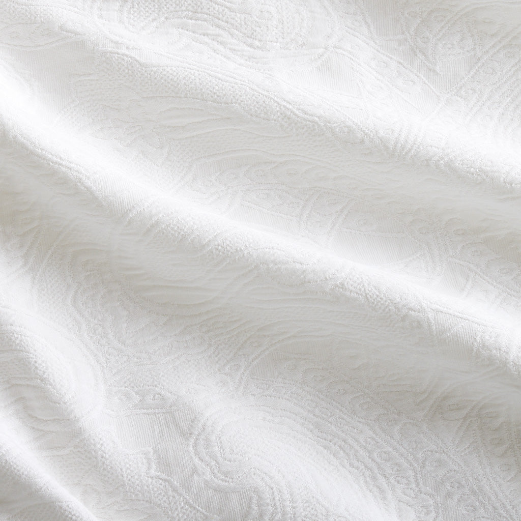 White cotton matelassé coverlet with subtle paisley pattern and rich texture.