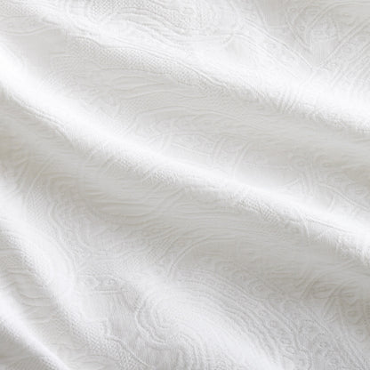 White cotton matelassé coverlet with subtle paisley pattern and rich texture.