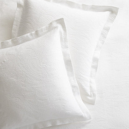 Two white cotton matelassé shams with subtle paisley pattern and 2-inch double-stitched hem.