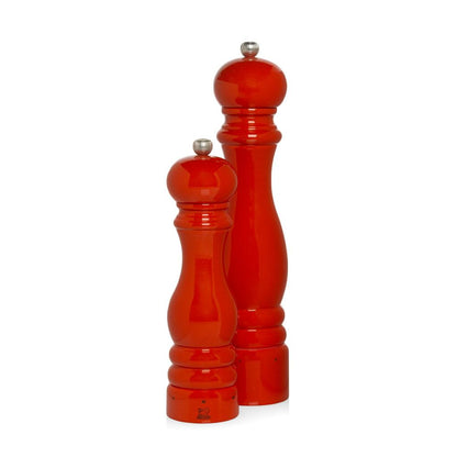 Two Peugeot Paris Exclusive International Orange 12" and 8" beechwood pepper mills with silver tops.