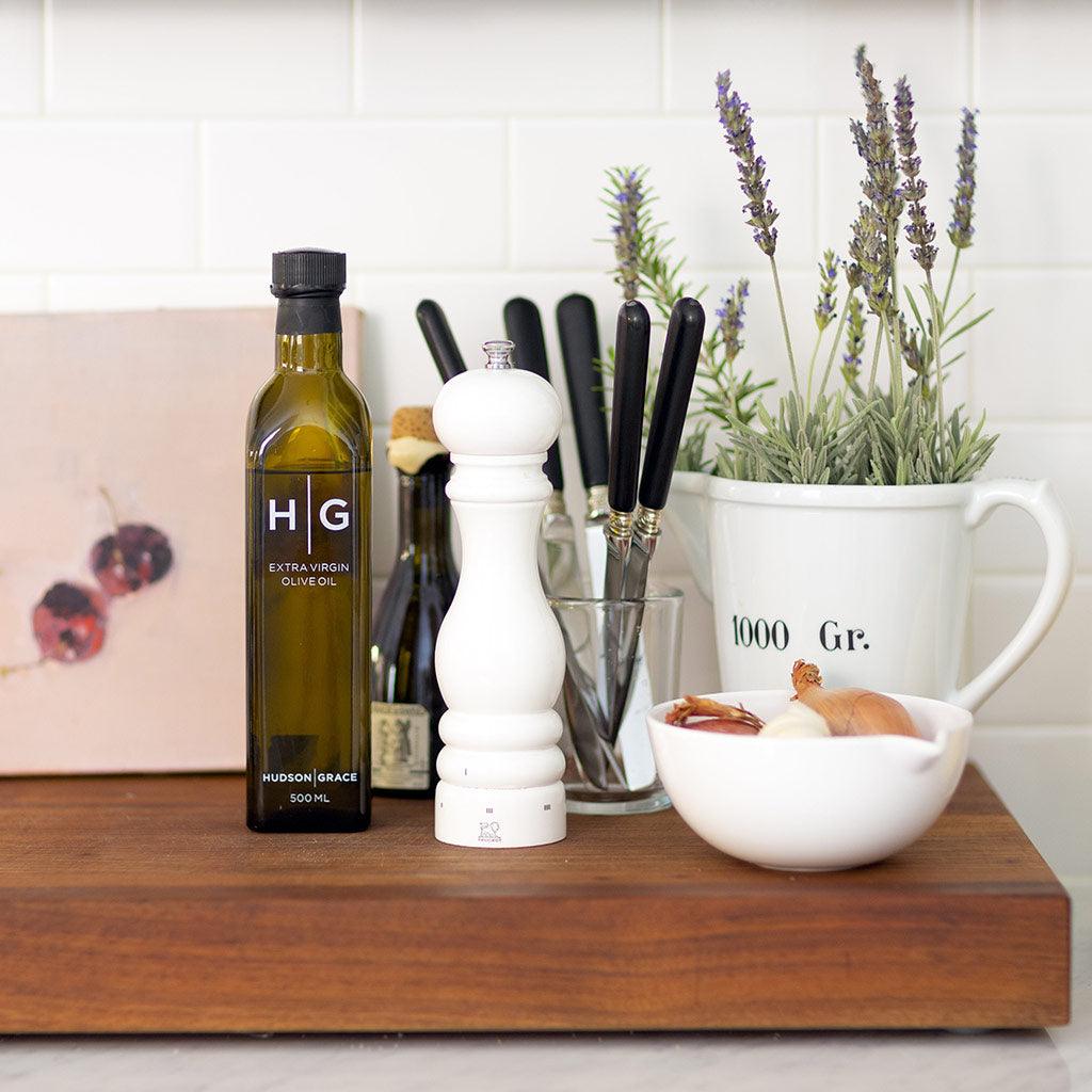 Peugeot Paris White Lacquer Pepper Mill, 12", on a wooden board with olive oil, knives, and lavender.