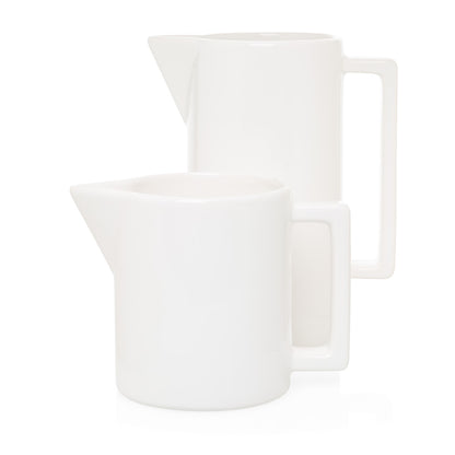 Two white ceramic pitchers, one large with a rectangular handle, one smaller.