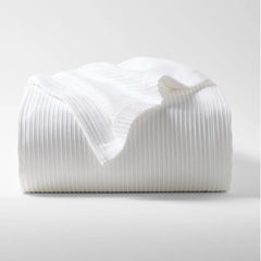 Folded white ribbed cotton matelassé coverlet with subtle texture.