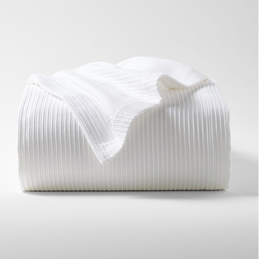Folded white ribbed cotton matelassé coverlet with subtle texture.