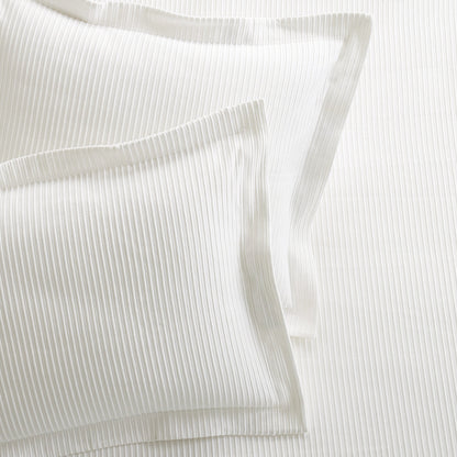 Two white ribbed cotton matelassé pillow shams with a 2" hem and mitered corners.