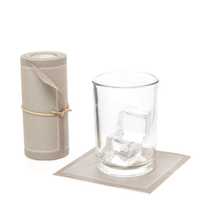 Sand tear-off cotton cocktail napkin roll with one napkin under a glass of ice.
