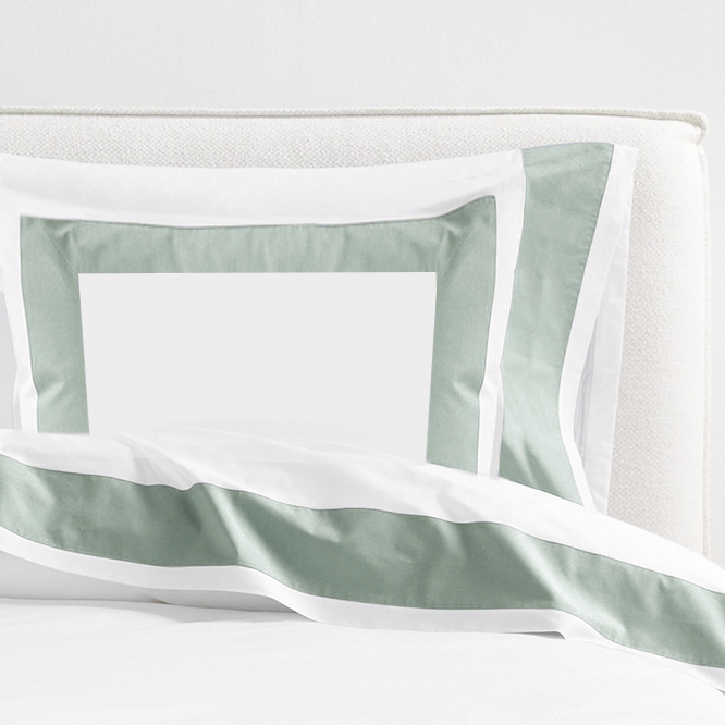 Seafoam Green Wide-Band Percale Pillow Sham with white border and bedding on a white headboard.