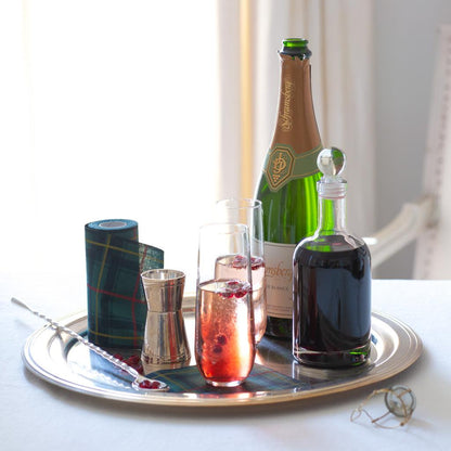 Silverplate long bar stirrer spoon with twisted stem on a tray with cocktails, jigger, and champagne.