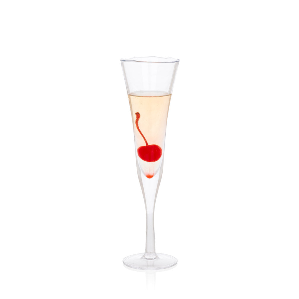 Clear, scissor-cut glass champagne flute with a rippled rim, filled with a light beverage and a red cherry.