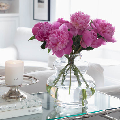 Sylvia Glass Vase, clear mouth-blown glass, 9.5"H, with pink peonies on a glass table.