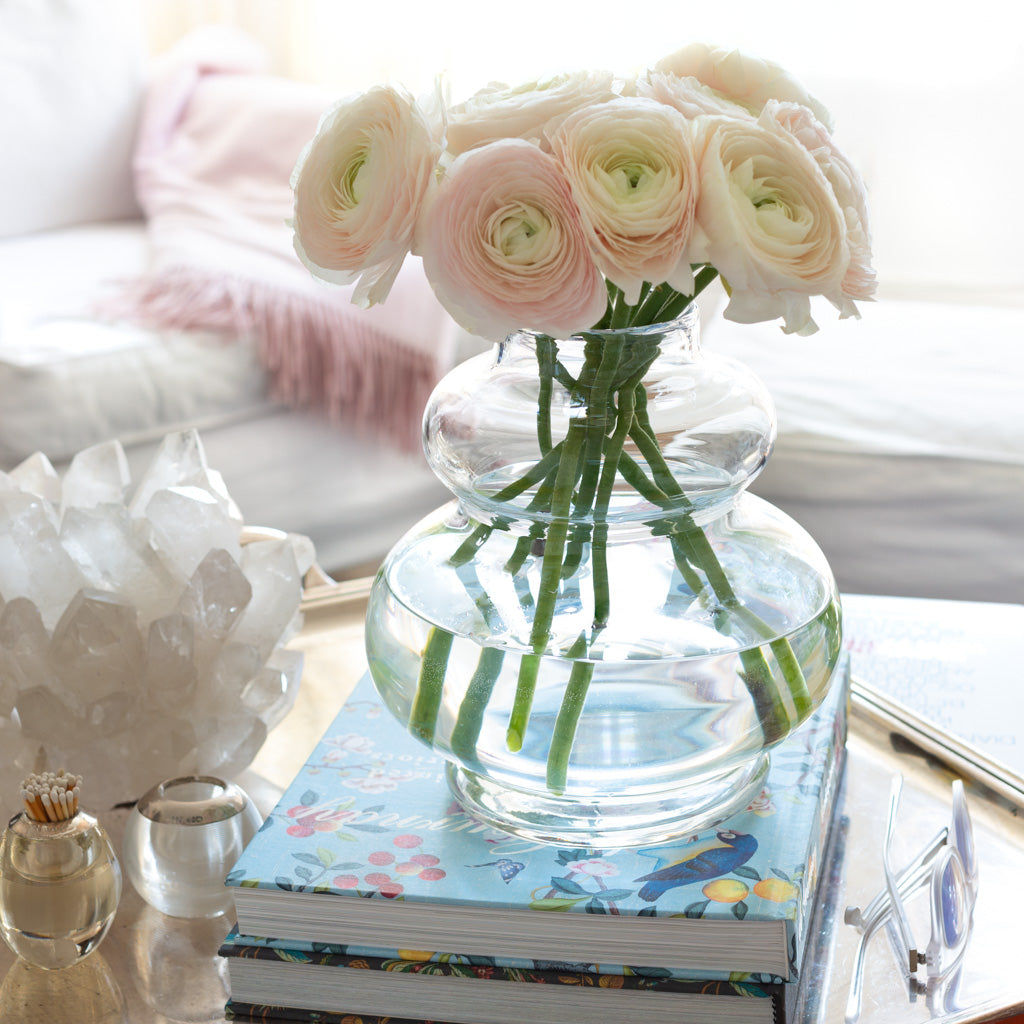Sylvia mouth-blown glass vase with a sculptural, honey dipper shape, holding light pink ranunculus.