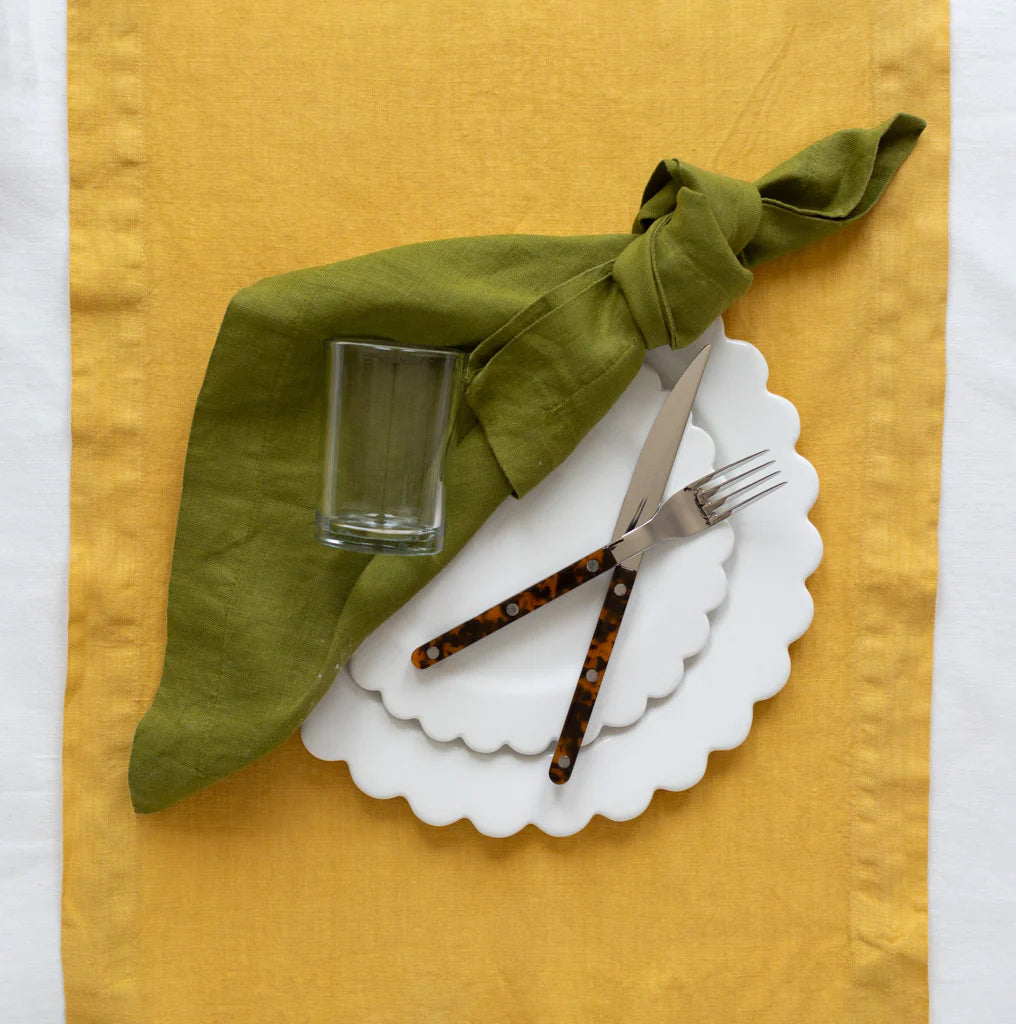 Tortoise Bistro 5-piece flatware set with stainless steel and tortoise acrylic handles on a white scalloped plate.
