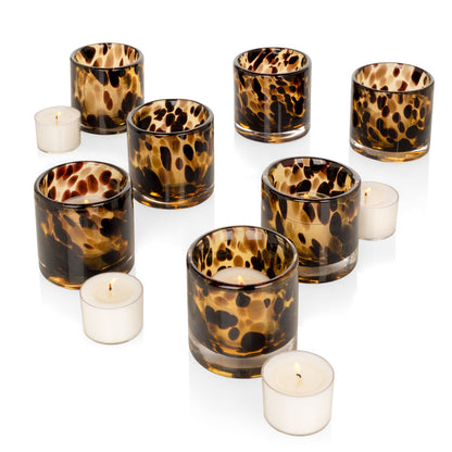 Set of seven tortoise pattern glass votive candle holders with lit tealights.