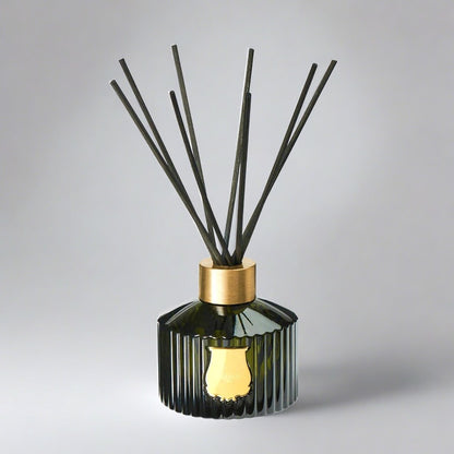 Trudon Cyrnos Scented Reed Diffuser: fluted dark green glass bottle with gold seal and black rattan sticks.