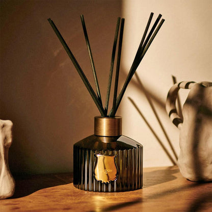 Trudon Ernesto Scented Reed Diffuser in a dark fluted glass bottle with a gold seal and black rattan sticks.