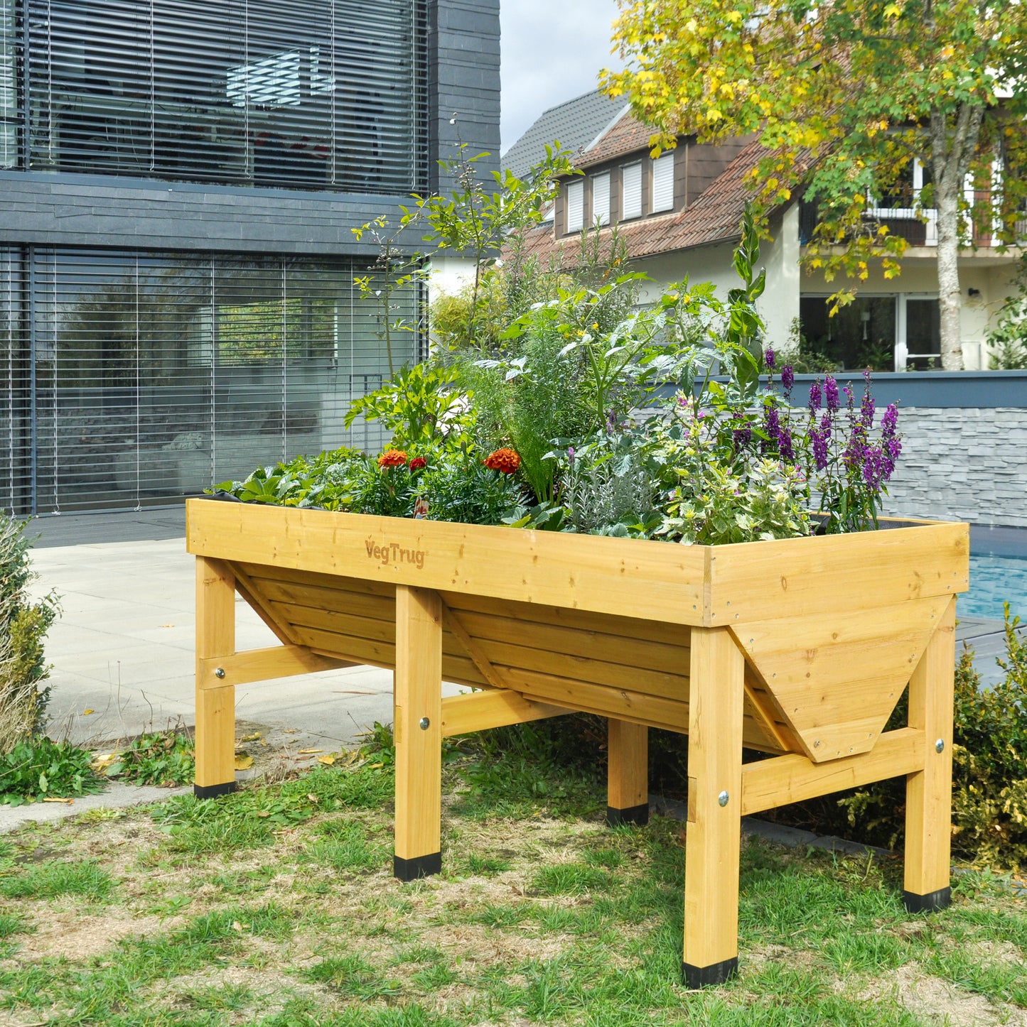 Light wood VegTrug Medium V-shaped raised garden planter, filled with various plants and flowers.