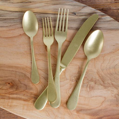 Vintage Oro 5-piece flatware set: gold-finished stainless steel dinner fork, salad fork, knife, soup spoon, teaspoon on wood.