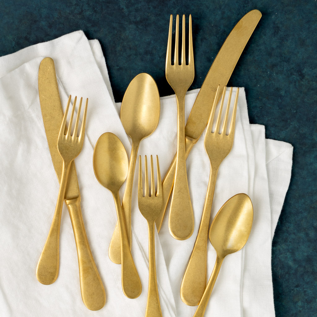 Vintage Oro gold 5-piece flatware set with neo-baroque design on a white napkin.