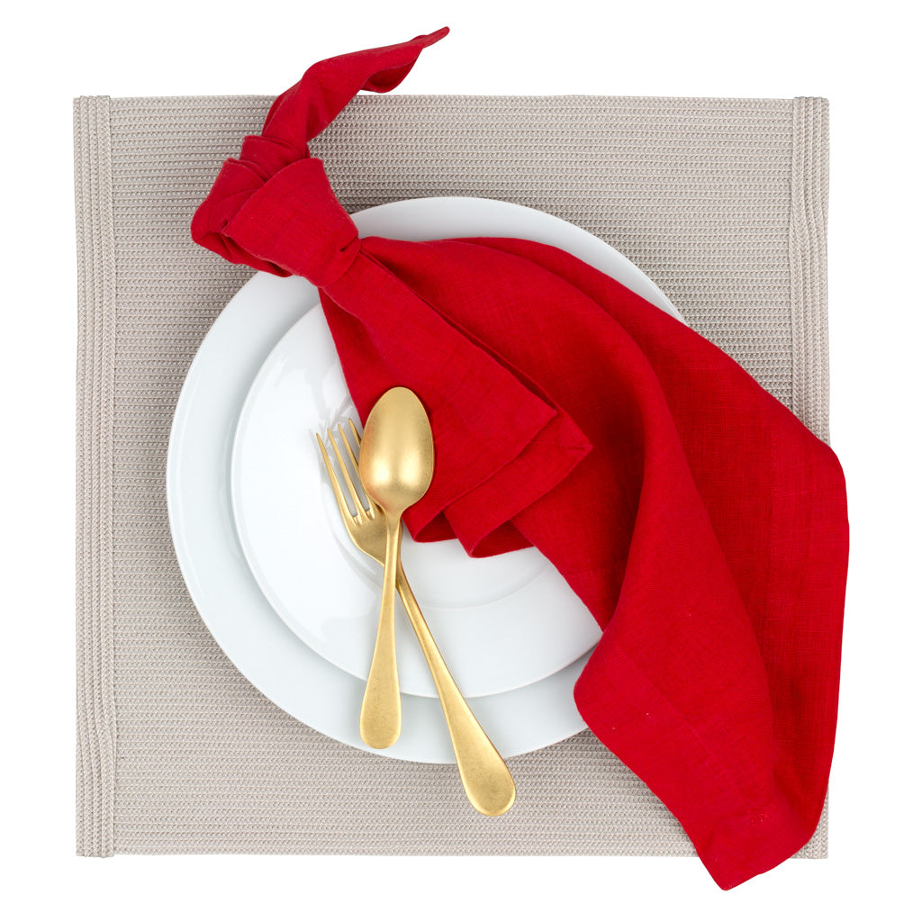 Vintage Oro gold 5-piece flatware set on white plates with a red napkin and beige placemat.