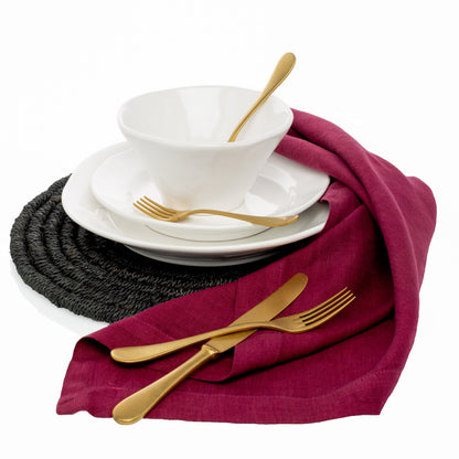 Vintage Oro 5-piece gold flatware set with white plates, bowl, and maroon napkin on a black placemat.