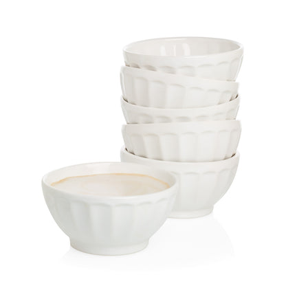 Stack of five white ceramic latte bowls and one bowl filled with a light beverage.